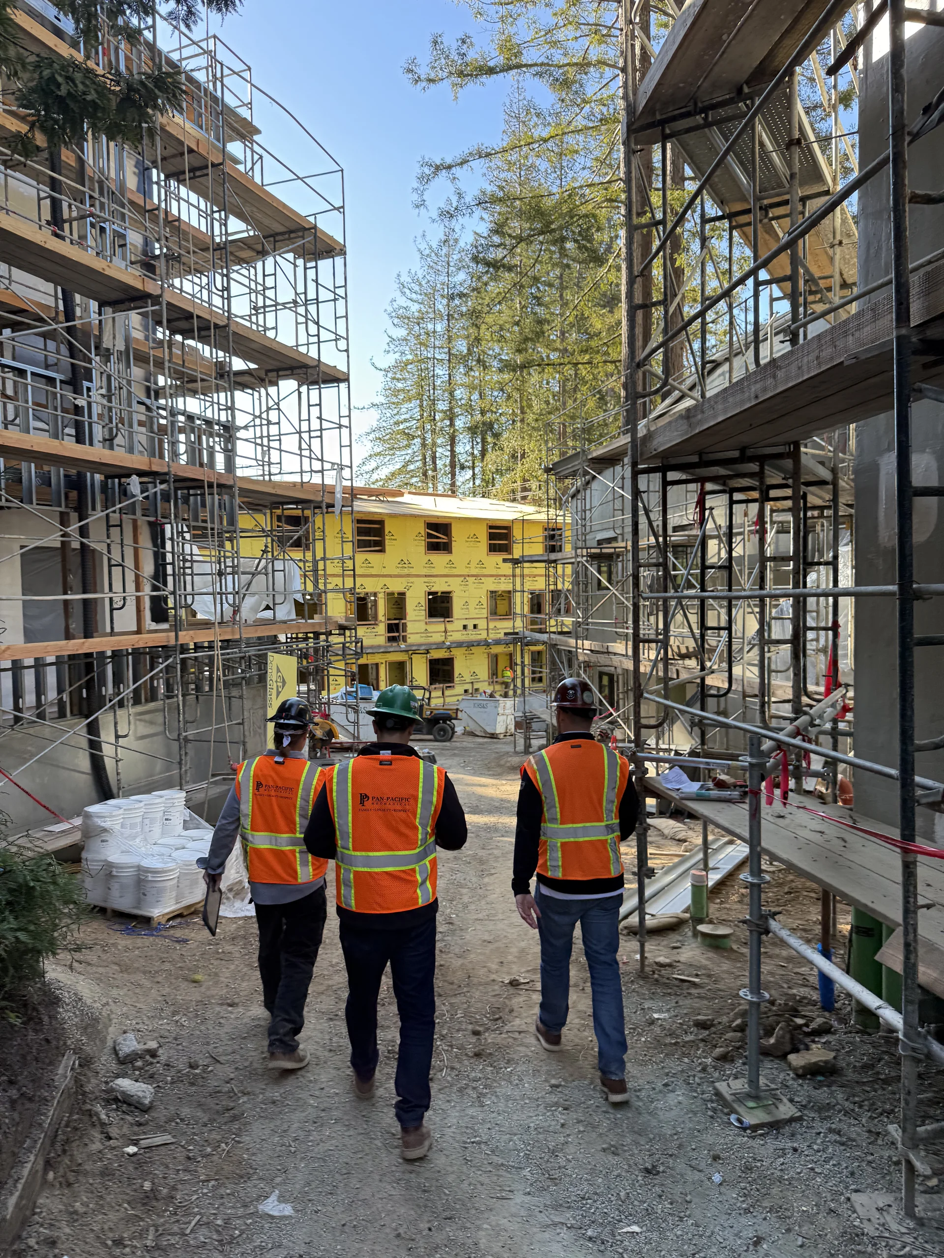 PPM crew members walking between scaffolded residence buildings at the Kresge College jobsite