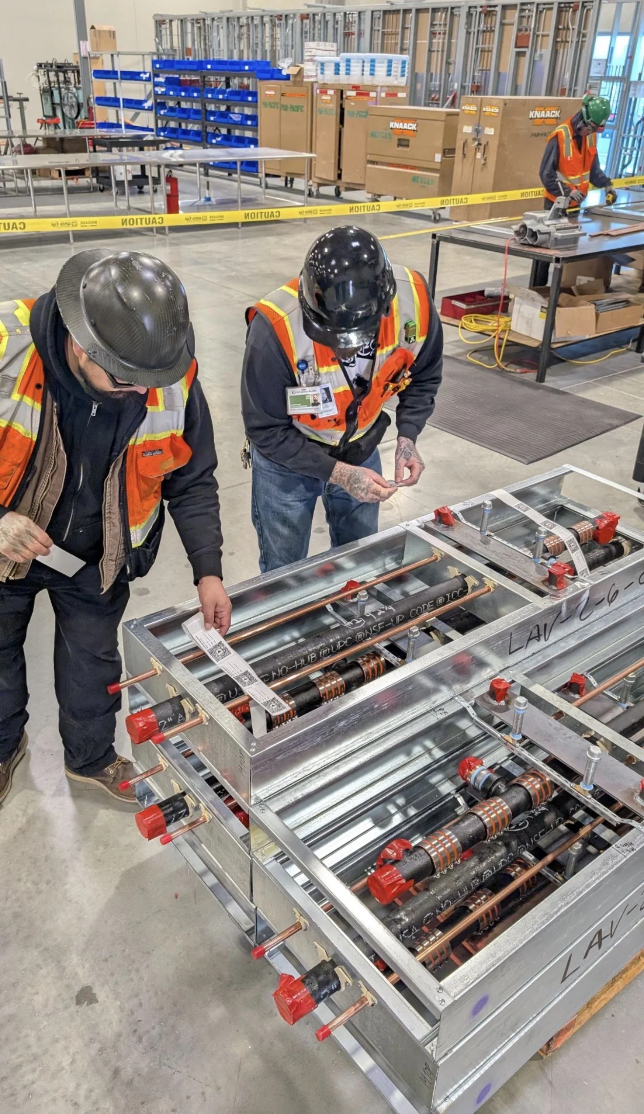 PPM fabricators inspecting prefabricated plumbing carrier assemblies in the Morgan Hill shop